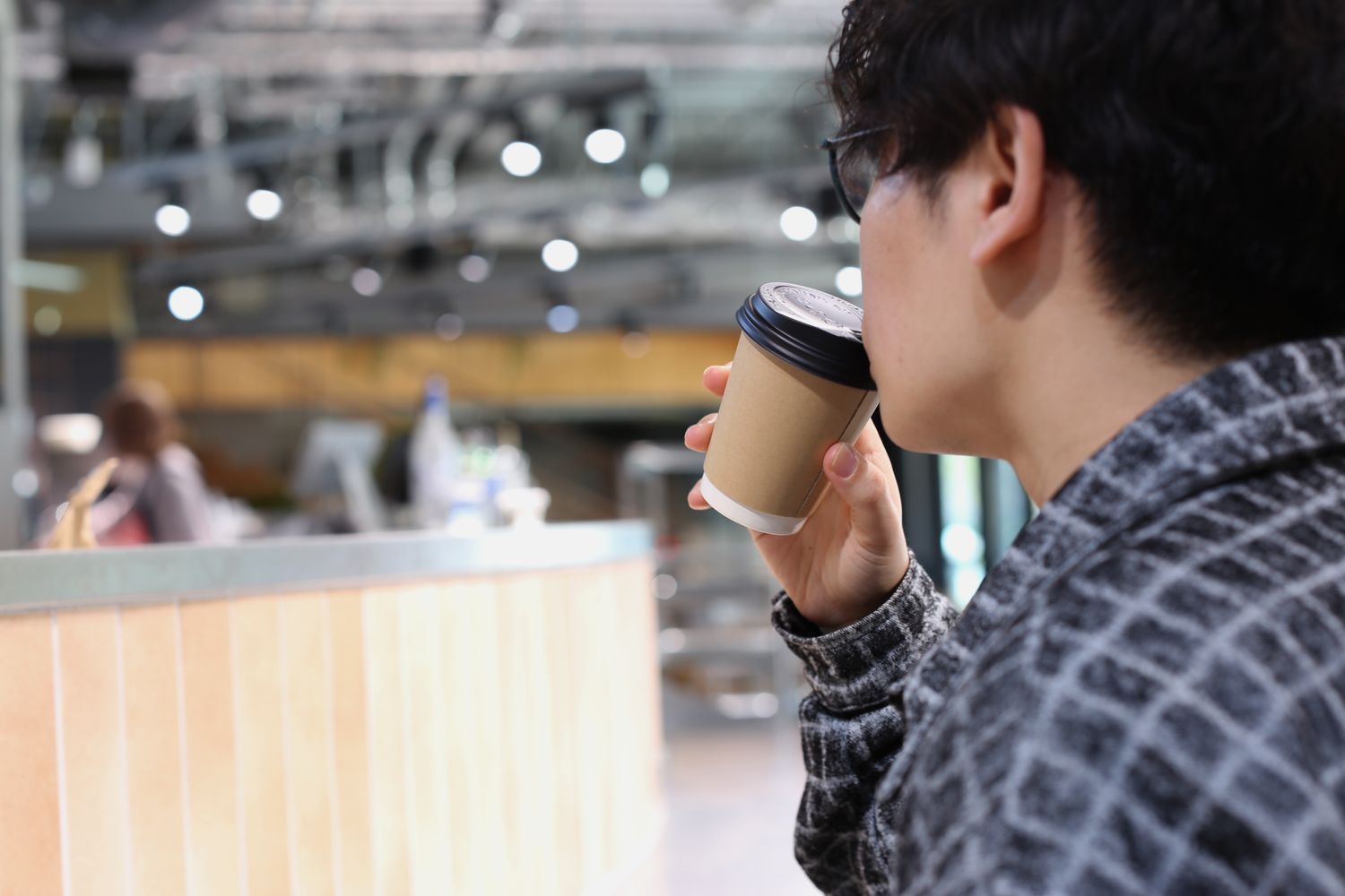 カウンターに背を向けて、カップのコーヒーを口に運んでいるお客さん