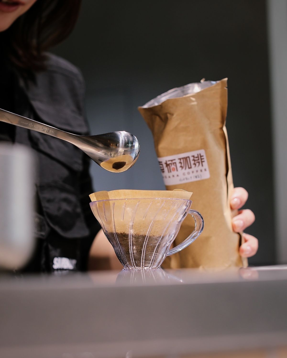 紙袋から計量スプーンでコーヒー豆をすくい、ドリッパーに入れているところ