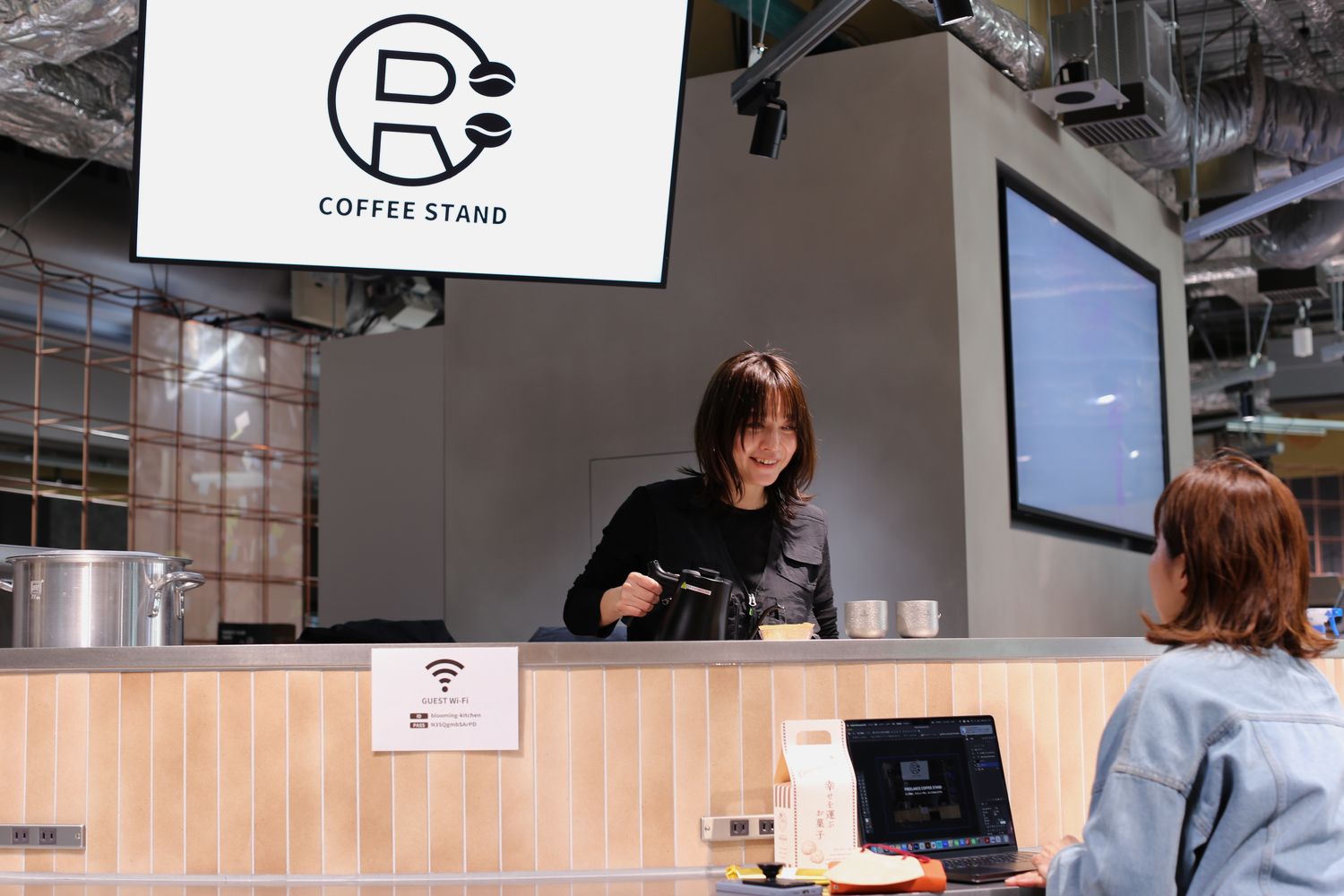 カウンターでコーヒーを淹れながら、お客さんと話しているところ
